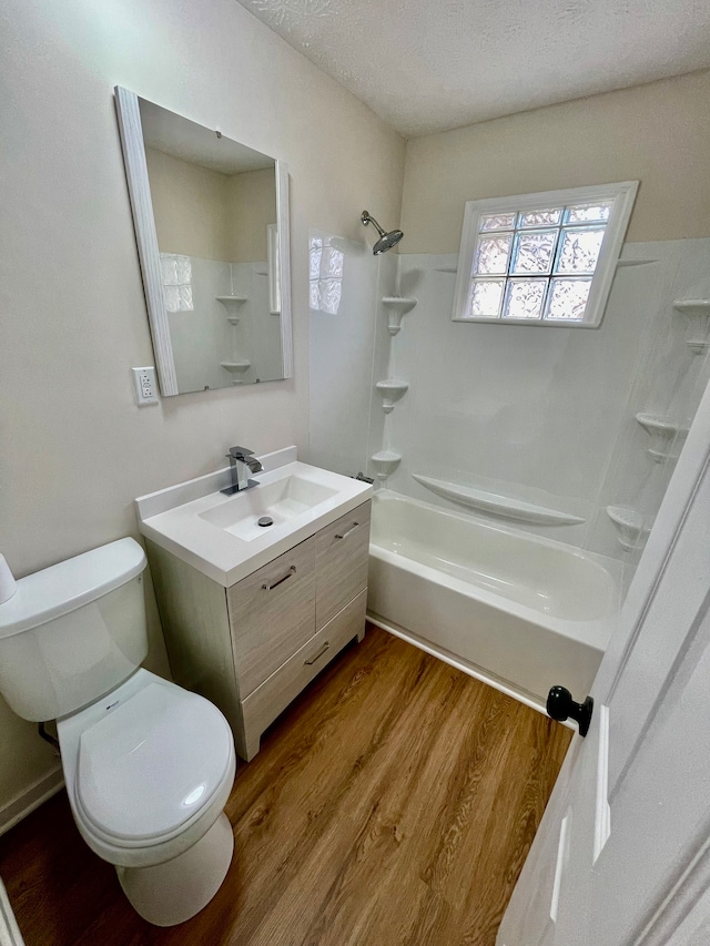 full bathroom featuring toilet, shower / bathing tub combination, wood-type flooring, a textured ceiling, and large vanity