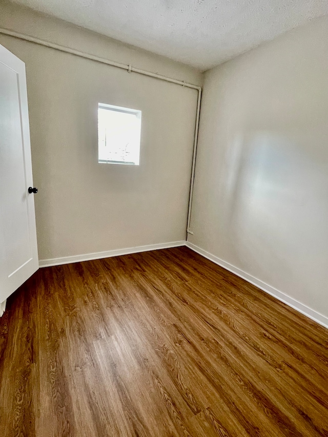 empty room featuring dark hardwood / wood-style flooring and a textured ceiling