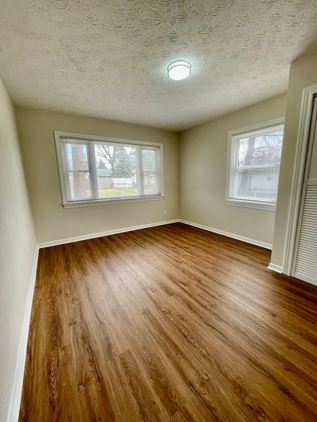 empty room with dark wood-type flooring, a textured ceiling, and a wealth of natural light