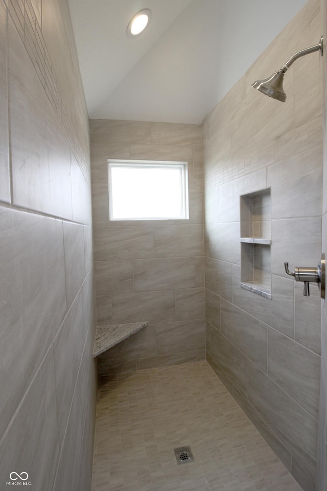 bathroom with a tile shower and vaulted ceiling