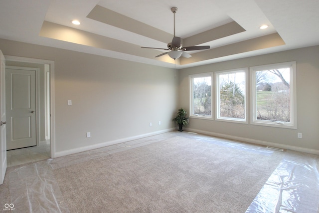 unfurnished room featuring a raised ceiling and ceiling fan