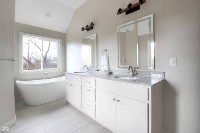 bathroom with vaulted ceiling, a bathing tub, and vanity