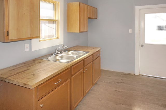 kitchen with sink, light wood-type flooring, and wood counters