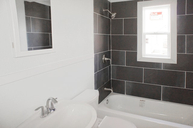 full bathroom featuring tiled shower / bath combo, toilet, and sink