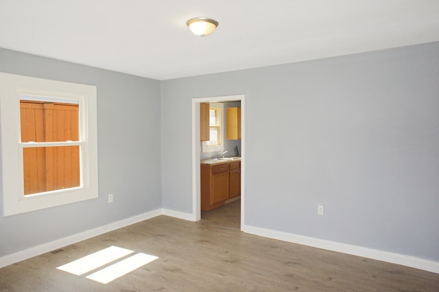 unfurnished room featuring sink and light hardwood / wood-style floors