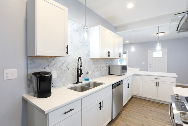 kitchen with appliances with stainless steel finishes, sink, tasteful backsplash, light wood-type flooring, and pendant lighting