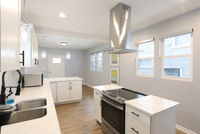 kitchen featuring decorative light fixtures, island range hood, stainless steel electric range oven, white cabinets, and light wood-type flooring