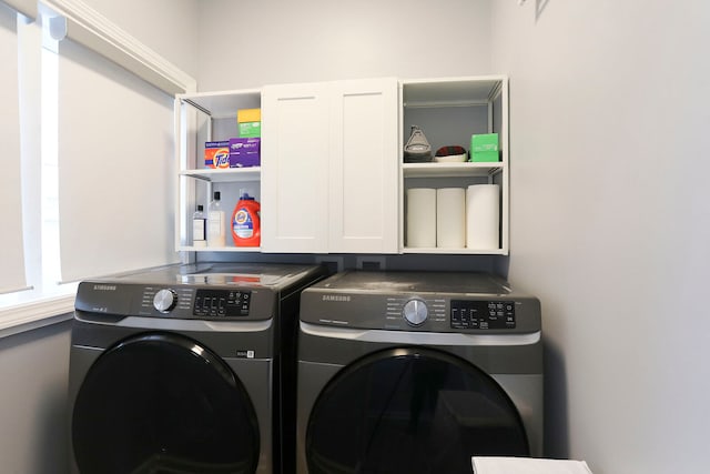 clothes washing area featuring washing machine and dryer and cabinets