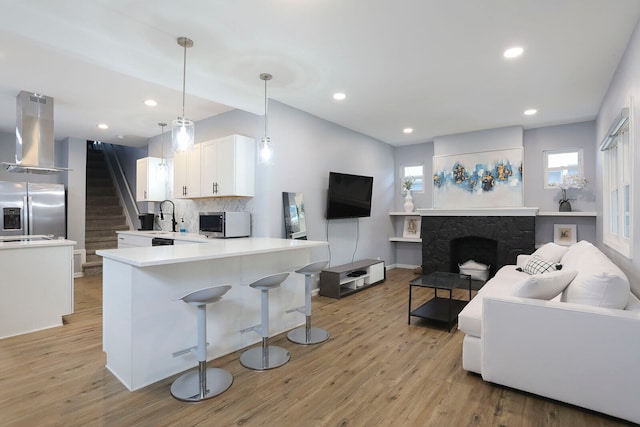 kitchen with appliances with stainless steel finishes, plenty of natural light, light wood-type flooring, and wall chimney exhaust hood