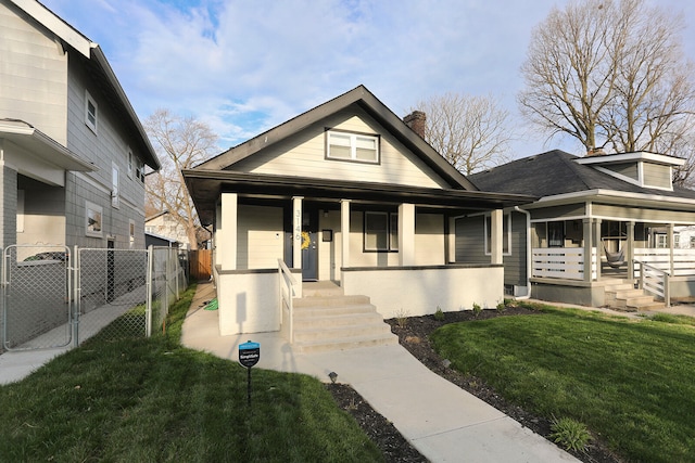 bungalow-style home featuring covered porch and a front yard