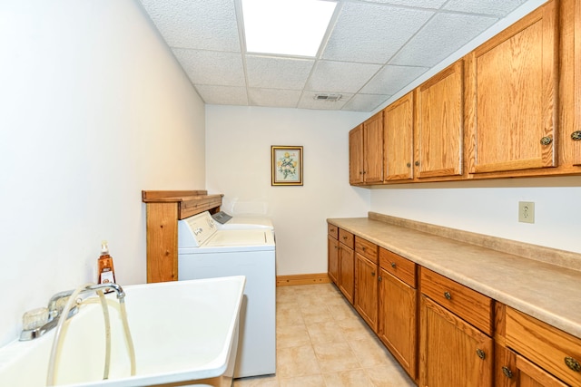 clothes washing area with washing machine and clothes dryer, cabinets, and light tile floors