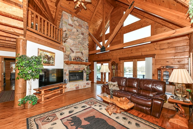 living room with a stone fireplace, high vaulted ceiling, wood-type flooring, and beamed ceiling