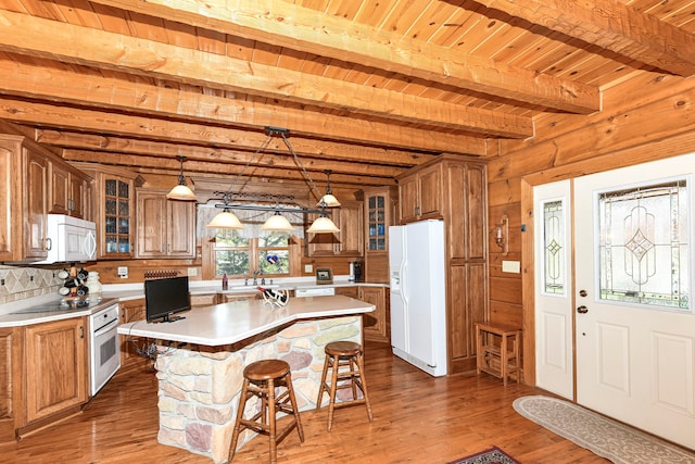 kitchen with hanging light fixtures, beamed ceiling, white appliances, a center island, and wood ceiling