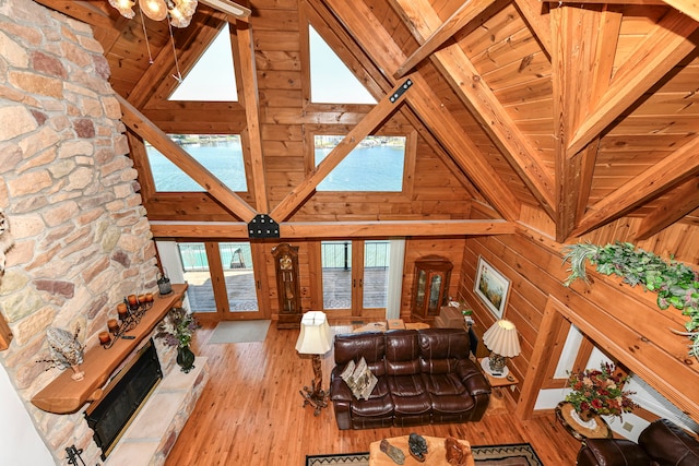 living room featuring wooden walls, wood ceiling, light wood-type flooring, and beamed ceiling