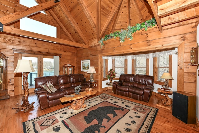 living room with beamed ceiling, high vaulted ceiling, a healthy amount of sunlight, and wood-type flooring