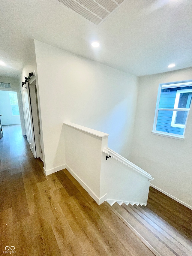 stairway with a barn door and wood-type flooring