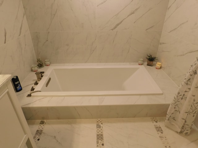 bathroom featuring vanity and a relaxing tiled tub