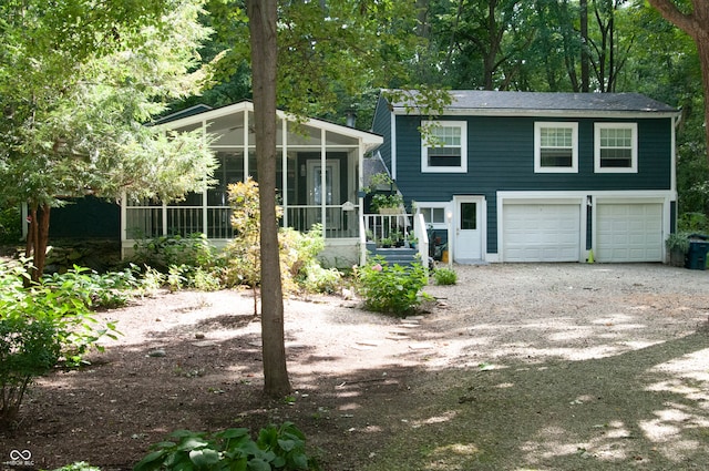 rear view of property with a garage and a sunroom