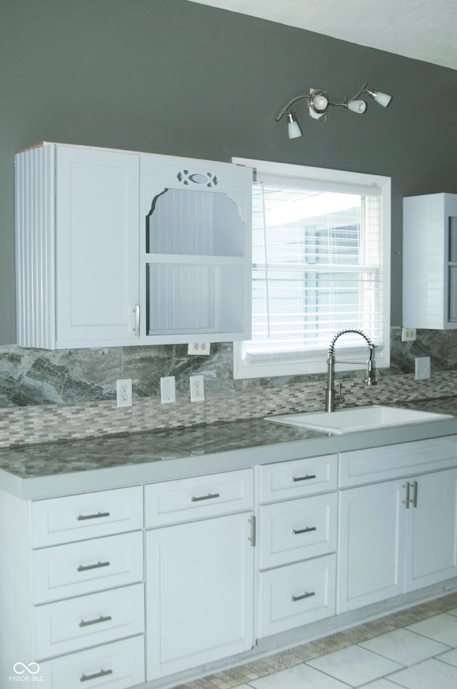 kitchen with white cabinets, dark stone countertops, decorative backsplash, and sink