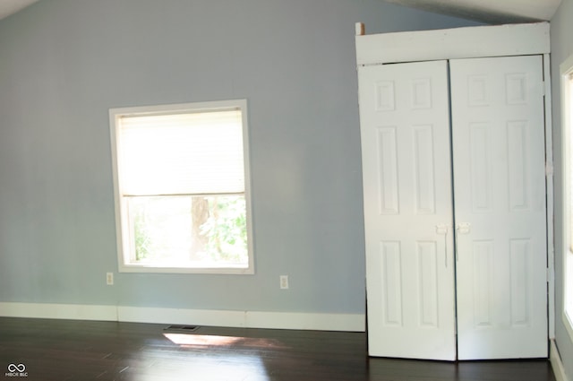 unfurnished bedroom with a closet, lofted ceiling, and dark hardwood / wood-style floors