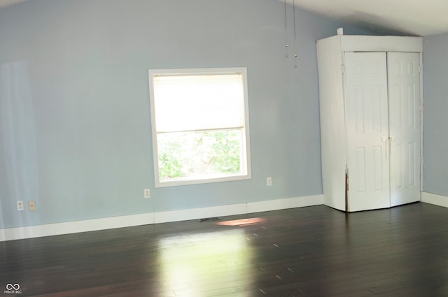 unfurnished bedroom featuring vaulted ceiling, a closet, and dark hardwood / wood-style flooring