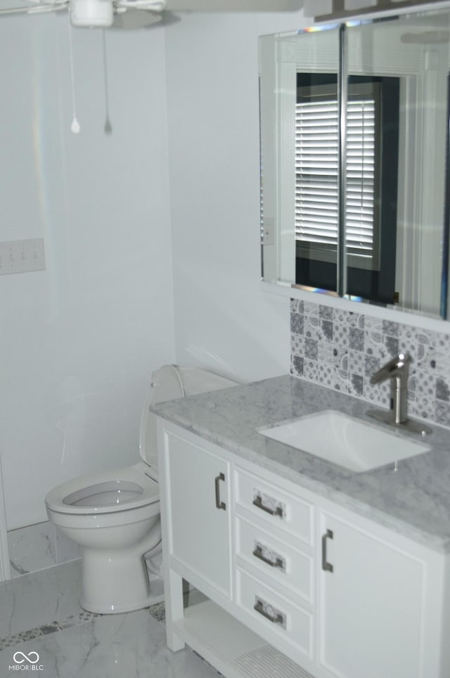 bathroom with toilet, decorative backsplash, and vanity