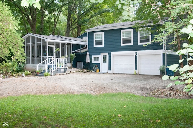 rear view of property featuring central AC unit, a garage, a sunroom, and a yard