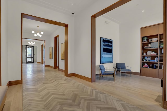 corridor with light parquet flooring and an inviting chandelier