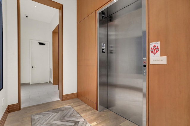 hallway featuring elevator and light hardwood / wood-style flooring