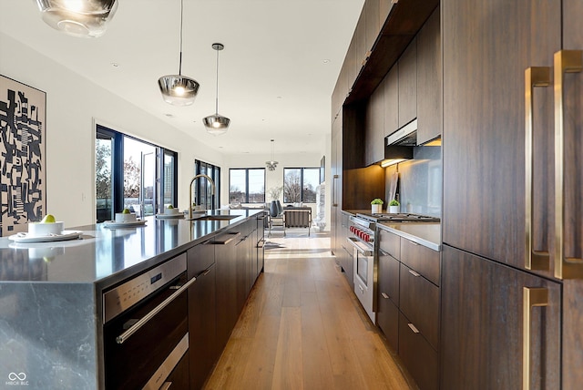 kitchen featuring a large island, light hardwood / wood-style floors, fridge, range with two ovens, and decorative light fixtures