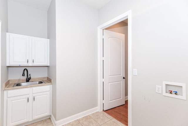 washroom featuring sink, light tile floors, washer hookup, and cabinets