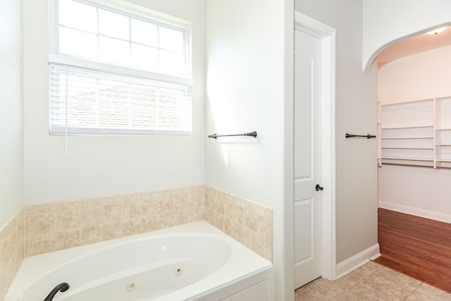 bathroom featuring a bath to relax in, a healthy amount of sunlight, and hardwood / wood-style flooring