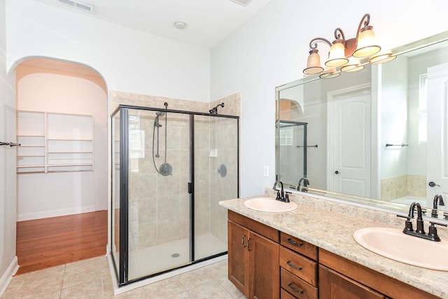 bathroom with independent shower and bath, large vanity, wood-type flooring, double sink, and a chandelier