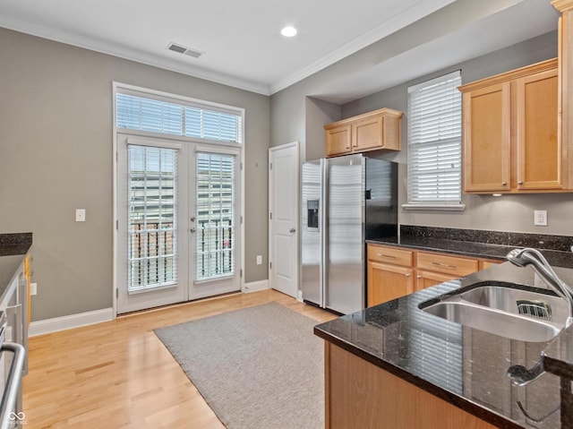 kitchen with sink, stainless steel fridge with ice dispenser, dark stone countertops, crown molding, and light hardwood / wood-style floors