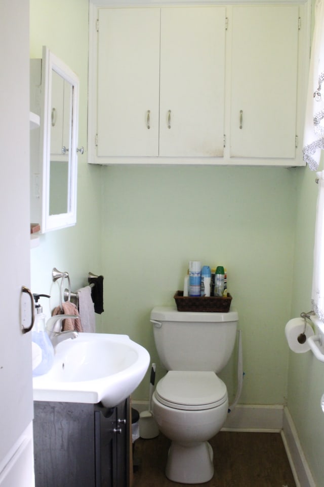 bathroom with baseboards, toilet, wood finished floors, and vanity