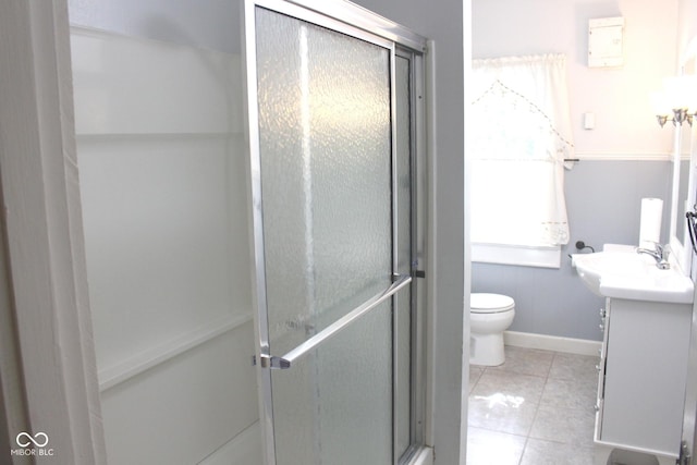 bathroom with toilet, a shower stall, tile patterned flooring, baseboards, and vanity