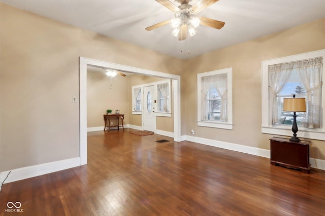 unfurnished room with a wealth of natural light, baseboards, ceiling fan, and wood finished floors