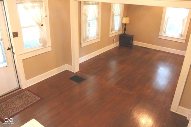 foyer entrance with dark wood-style floors, visible vents, and baseboards