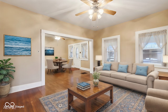 living area with baseboards, wood finished floors, and a ceiling fan