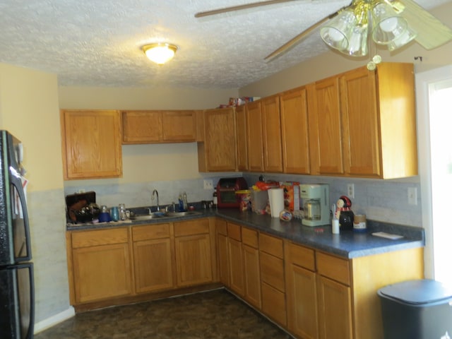 kitchen featuring black refrigerator, sink, tasteful backsplash, ceiling fan, and a textured ceiling