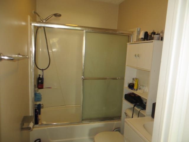 full bathroom featuring toilet, shower / bath combination with glass door, and vanity