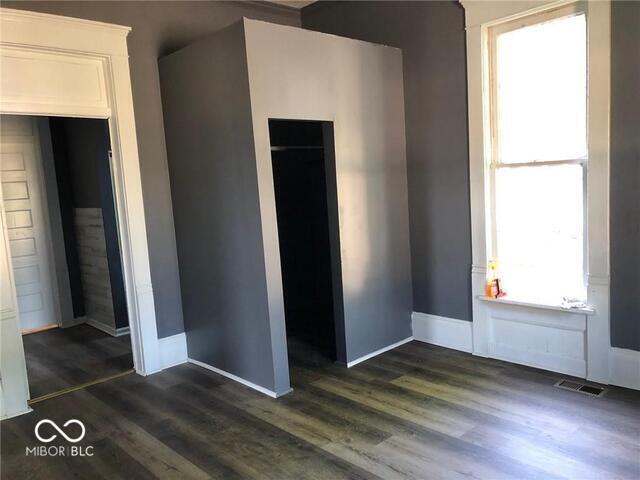 unfurnished bedroom with a closet and dark wood-type flooring