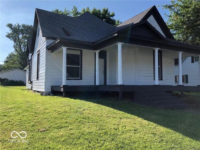 bungalow-style home featuring covered porch and a front lawn