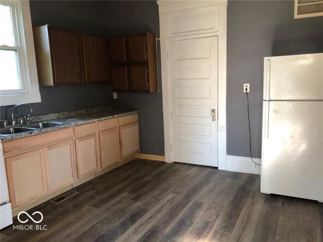 kitchen featuring dark hardwood / wood-style flooring, white fridge, and sink