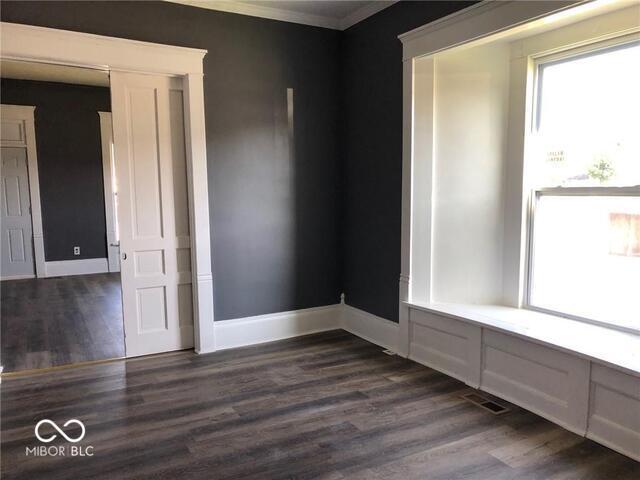 spare room featuring crown molding and dark hardwood / wood-style floors