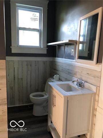 bathroom featuring wooden walls, vanity, hardwood / wood-style flooring, and toilet