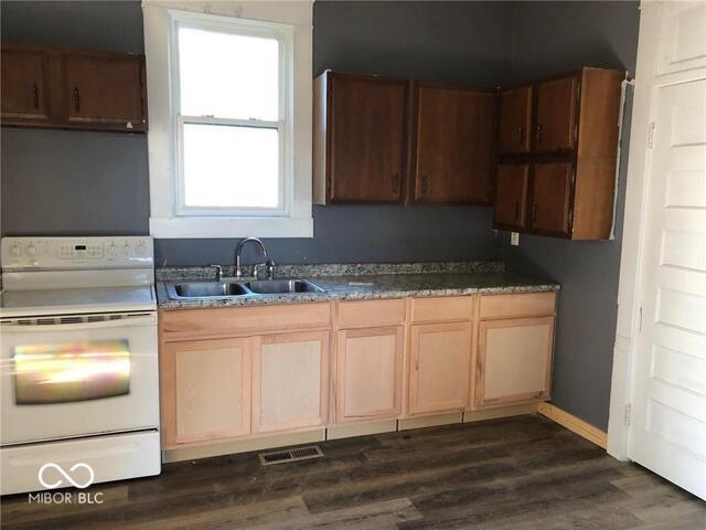 kitchen featuring stove, dark hardwood / wood-style floors, and sink