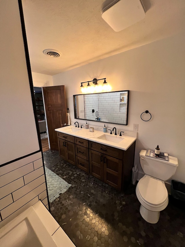 bathroom with oversized vanity, dual sinks, and toilet