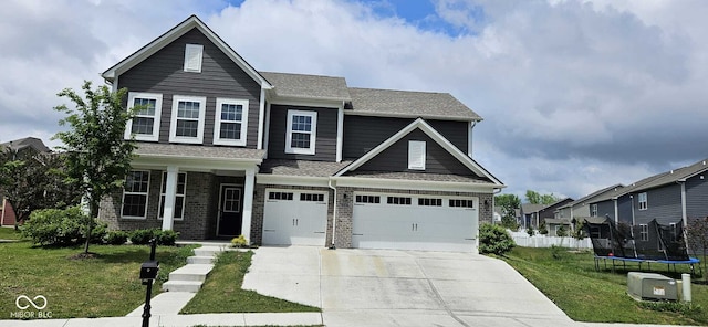 craftsman inspired home featuring a garage, a front lawn, and a trampoline