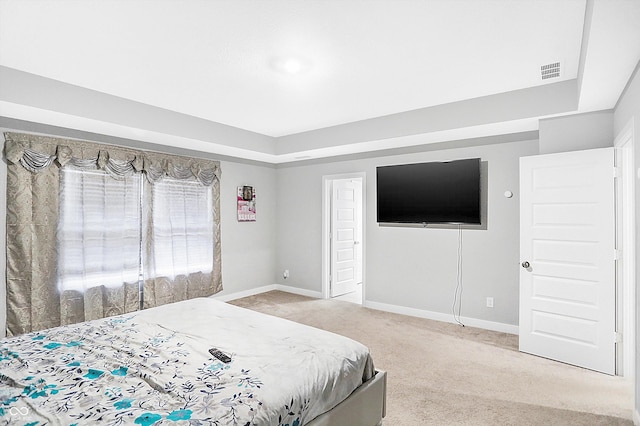 bedroom with light carpet and a raised ceiling